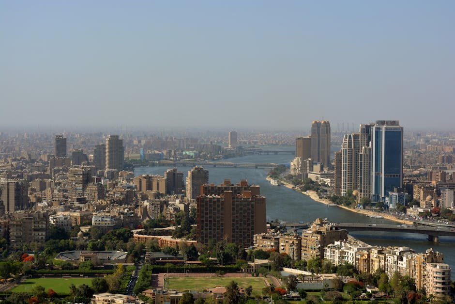 Aerial panorama of Cairo cityscape featuring modern skyscrapers and the Nile River.