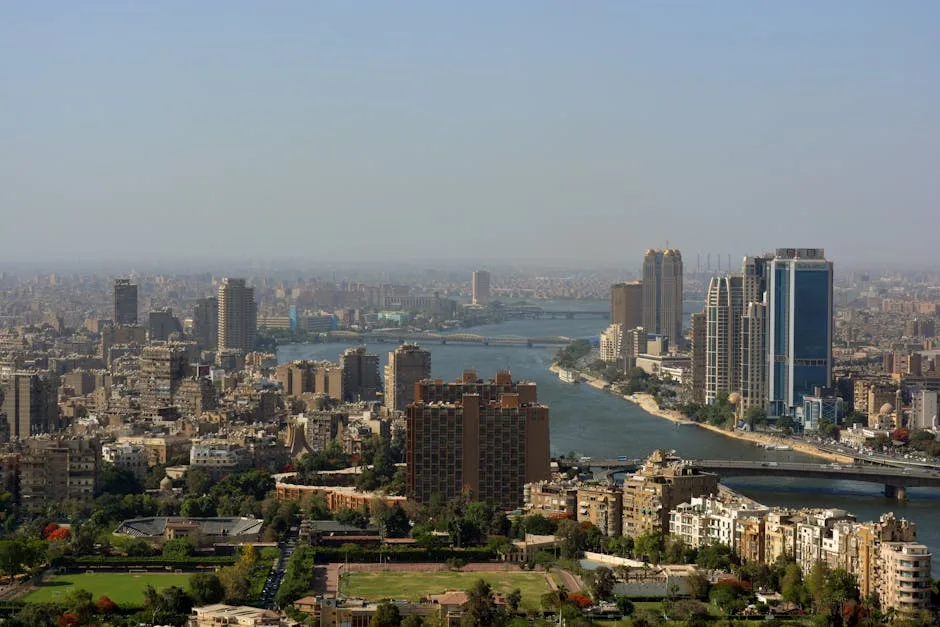 Aerial panorama of Cairo cityscape featuring modern skyscrapers and the Nile River.